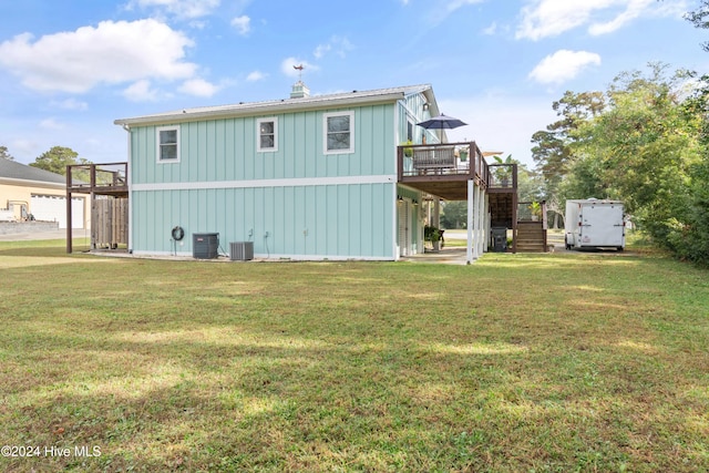 back of house with central air condition unit, a wooden deck, and a yard