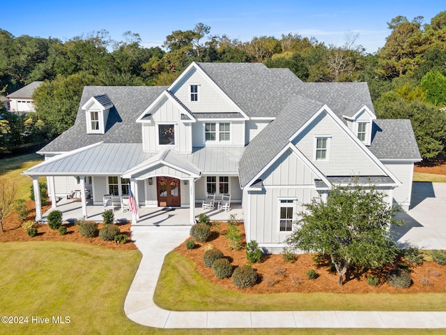 modern inspired farmhouse featuring covered porch and a front yard