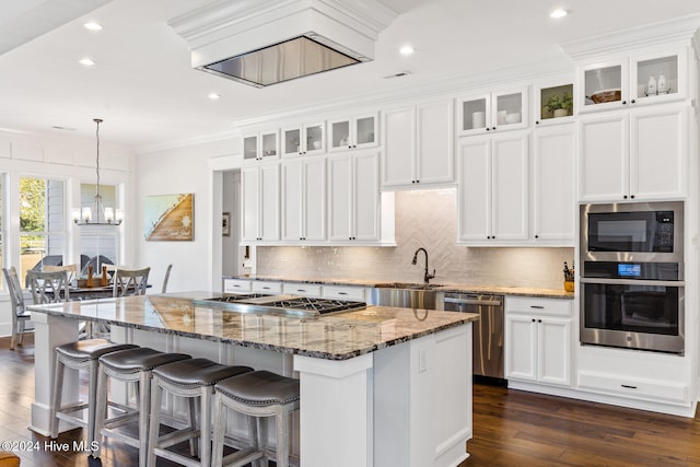 kitchen with dark hardwood / wood-style flooring, ornamental molding, stainless steel appliances, stone counters, and a center island