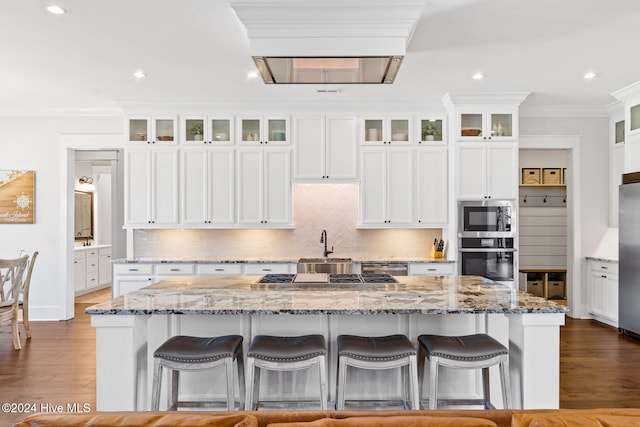 kitchen featuring white cabinets, a large island, stainless steel appliances, and a breakfast bar