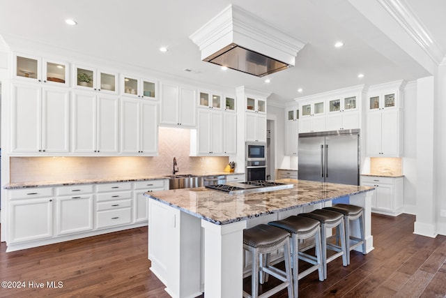 kitchen with built in appliances, white cabinetry, a kitchen island, and dark wood-type flooring