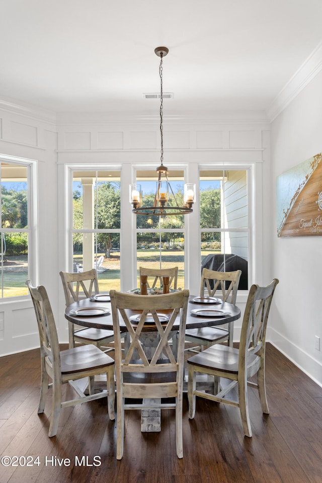 dining room featuring dark hardwood / wood-style floors, ornamental molding, a wealth of natural light, and an inviting chandelier