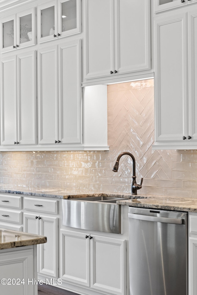 kitchen featuring light stone countertops, backsplash, sink, dishwasher, and white cabinetry