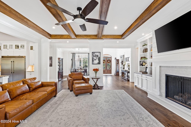 living room with ceiling fan, dark wood-type flooring, beamed ceiling, a fireplace, and ornamental molding