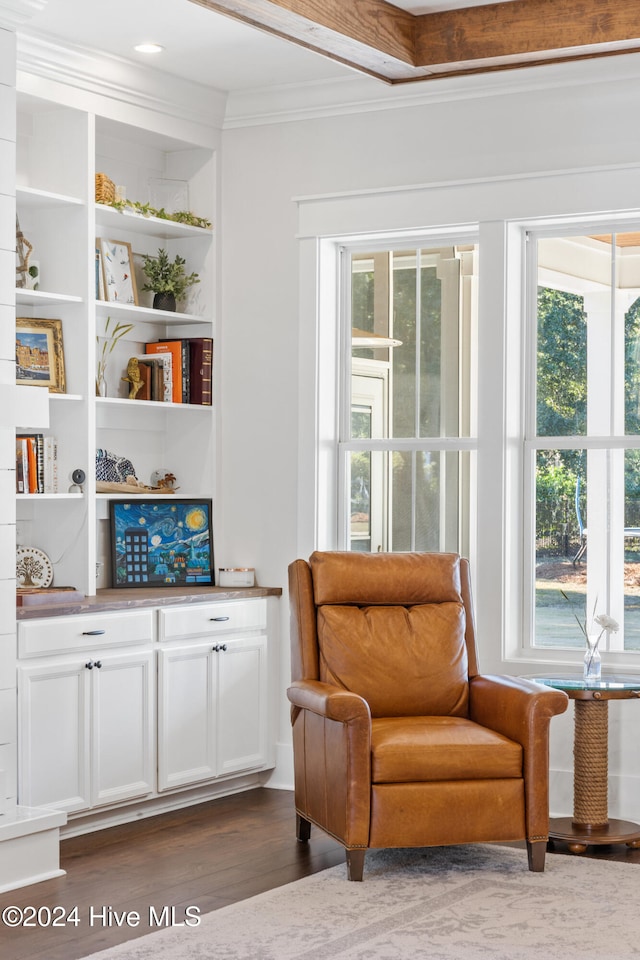 sitting room with beam ceiling, ornamental molding, and dark wood-type flooring