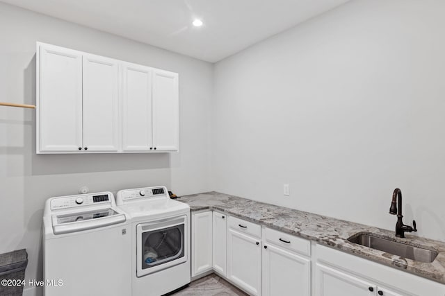 laundry area featuring cabinets, washer and dryer, and sink