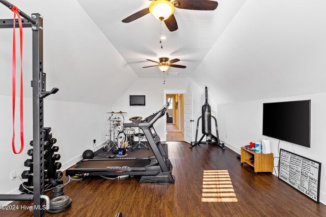 workout room with ceiling fan, dark wood-type flooring, and vaulted ceiling