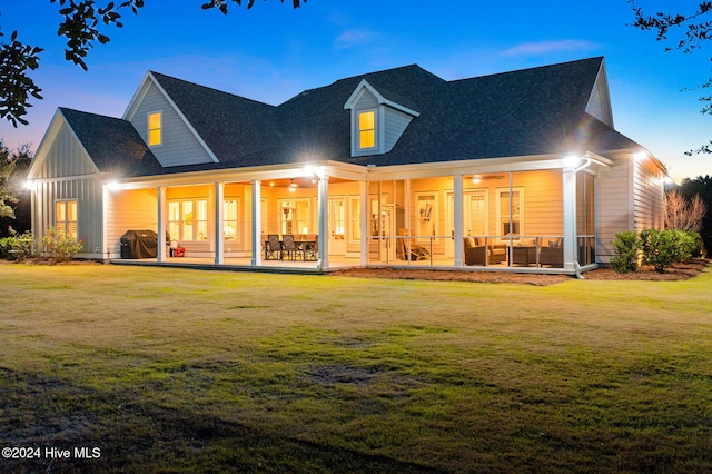 back house at dusk with a lawn, a patio area, and an outdoor hangout area