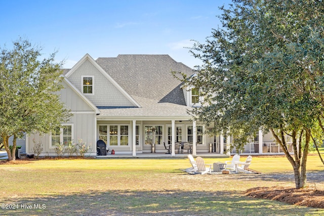 rear view of house with a patio, a fire pit, and a lawn