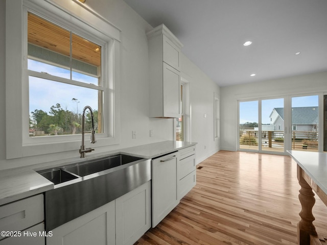 kitchen featuring white dishwasher, white cabinetry, sink, and light hardwood / wood-style flooring