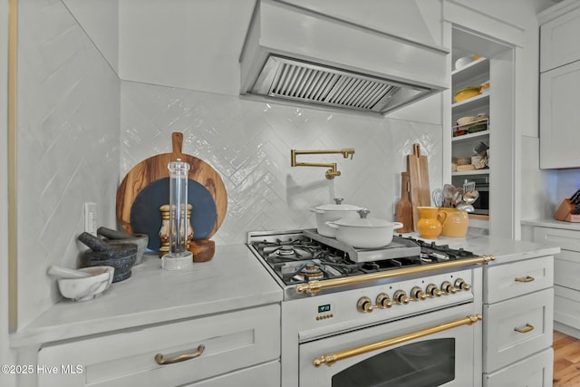 kitchen featuring high end white range oven, white cabinetry, backsplash, and exhaust hood