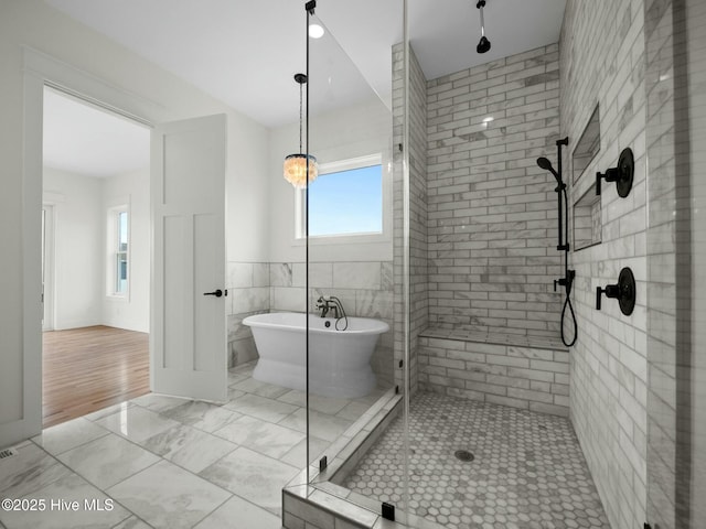 bathroom featuring plus walk in shower and tile walls