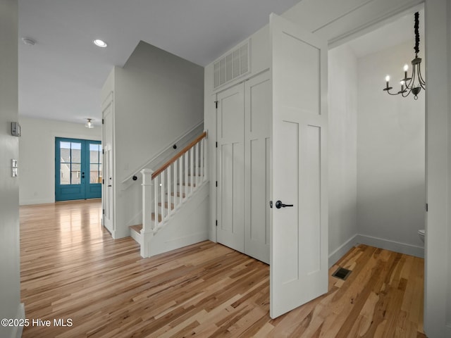 staircase featuring wood-type flooring and an inviting chandelier