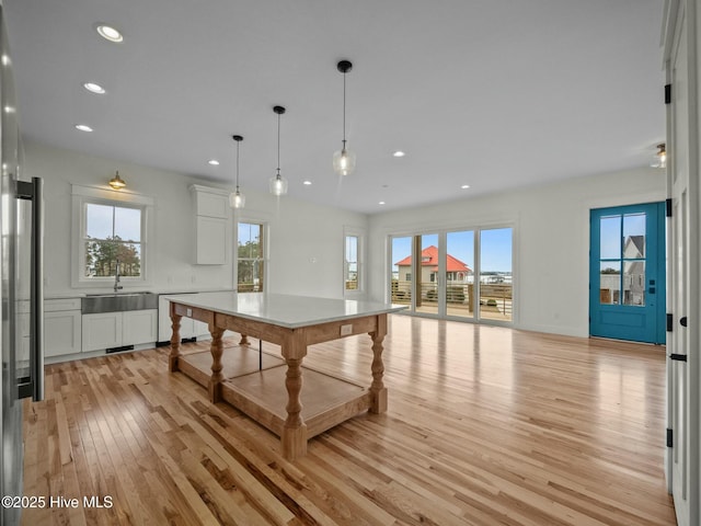 kitchen featuring pendant lighting, dishwasher, white cabinets, light hardwood / wood-style flooring, and a kitchen island