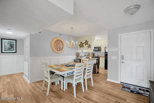 dining area featuring a chandelier, a textured ceiling, and light hardwood / wood-style floors