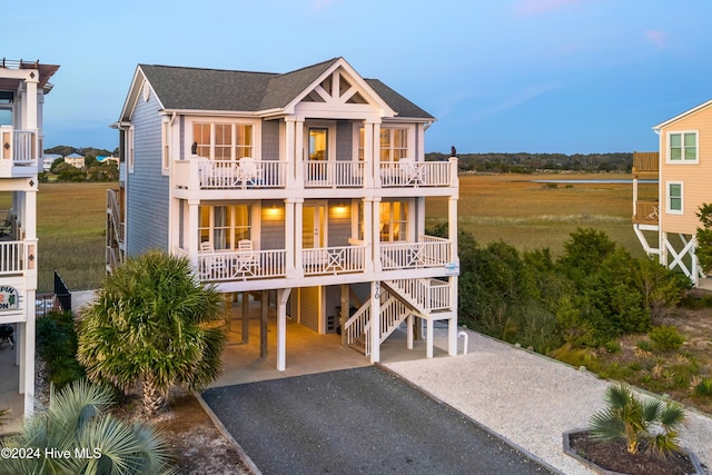 view of front of property with driveway, a shingled roof, a balcony, a porch, and a carport