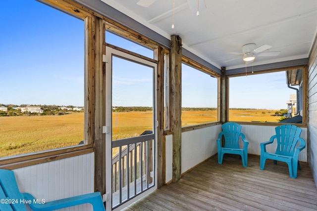 sunroom featuring a rural view and a ceiling fan