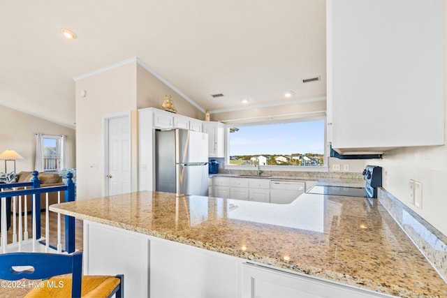 kitchen featuring a peninsula, range, freestanding refrigerator, and white cabinetry