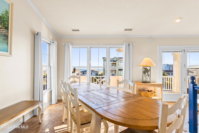 dining space with light tile patterned floors, ornamental molding, a textured ceiling, and visible vents