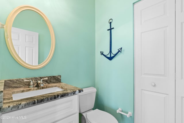 bathroom with a closet, vanity, and toilet