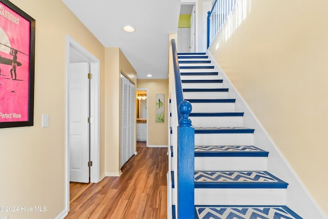 stairs featuring baseboards, wood finished floors, and recessed lighting