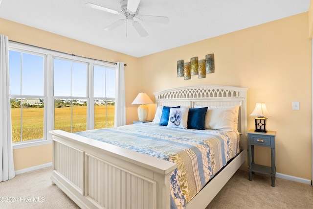 bedroom featuring ceiling fan, baseboards, and light colored carpet