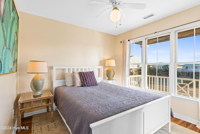 bedroom featuring a ceiling fan, baseboards, visible vents, and wood finished floors