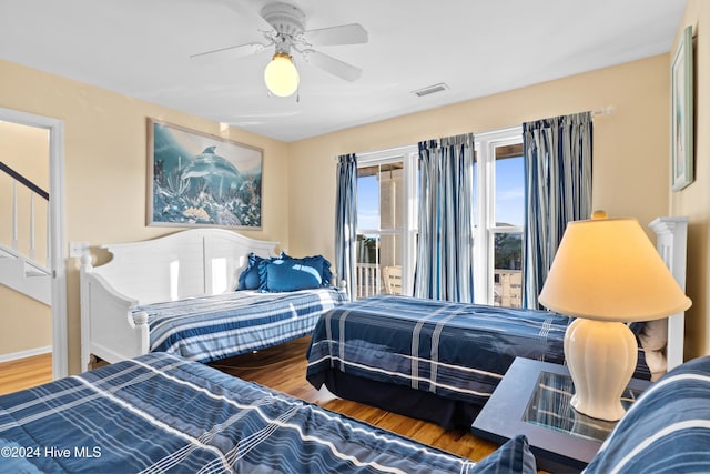 bedroom featuring ceiling fan, wood finished floors, visible vents, baseboards, and access to outside