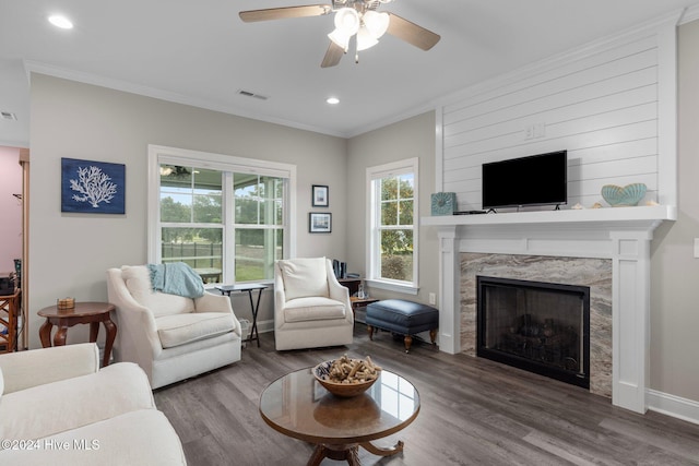 living room featuring a high end fireplace, wood-type flooring, and crown molding