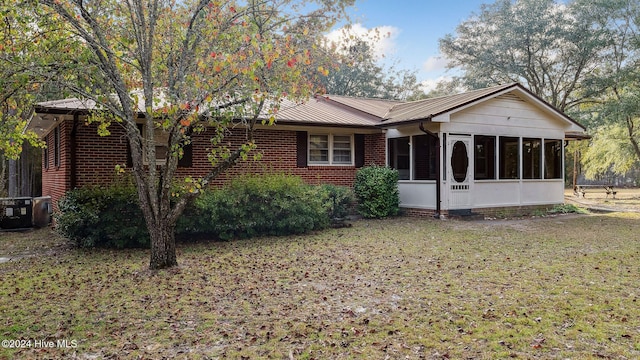 view of front of property with central AC unit, a sunroom, and a front yard