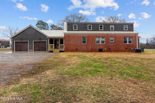 view of front of house with cooling unit, a garage, and a front lawn