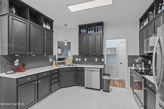 kitchen featuring sink, appliances with stainless steel finishes, tasteful backsplash, decorative light fixtures, and light hardwood / wood-style flooring