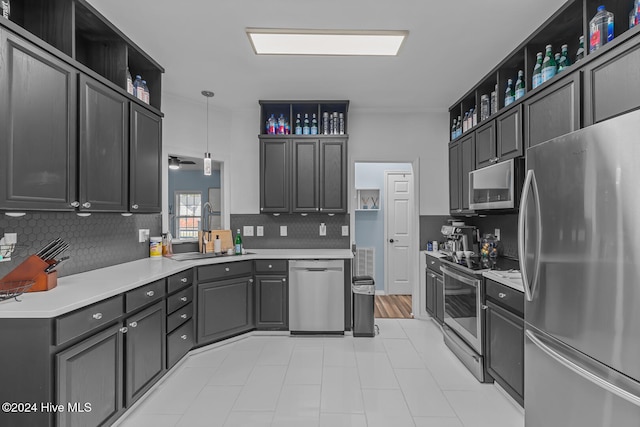 kitchen featuring stainless steel appliances, decorative backsplash, hanging light fixtures, sink, and ceiling fan