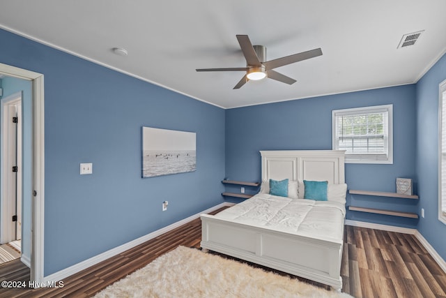 bedroom with ornamental molding, dark wood-type flooring, and ceiling fan