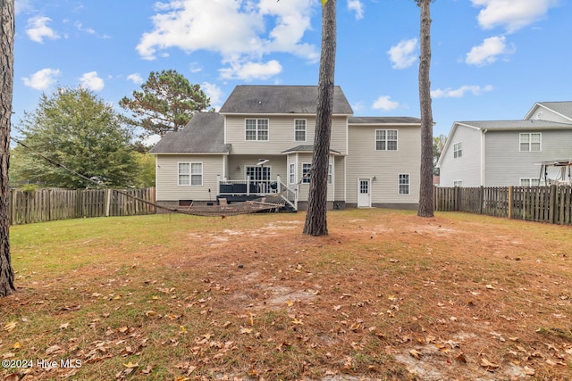 back of property with a wooden deck and a yard