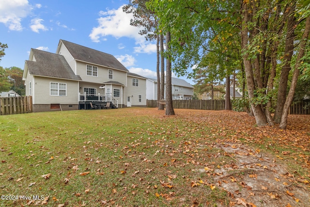 rear view of property featuring a lawn and a wooden deck