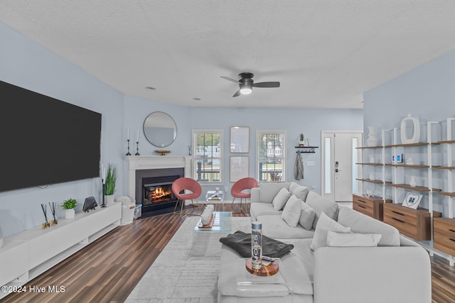 living room with dark hardwood / wood-style flooring, a textured ceiling, and ceiling fan