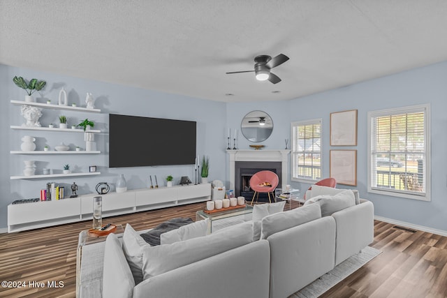 living room featuring hardwood / wood-style floors, ceiling fan, and a textured ceiling