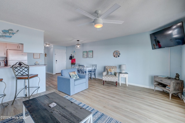 living room with light hardwood / wood-style floors, ceiling fan, and a textured ceiling