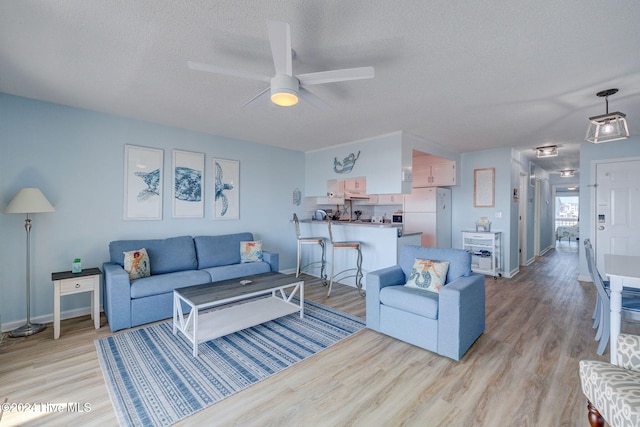 living room featuring a textured ceiling, light hardwood / wood-style floors, and ceiling fan