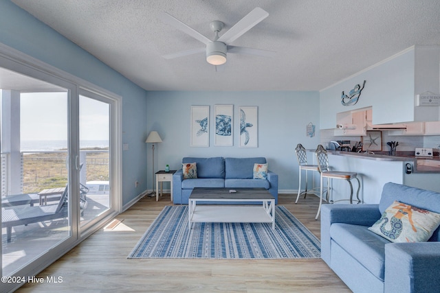 living room featuring a textured ceiling, ceiling fan, and light hardwood / wood-style flooring