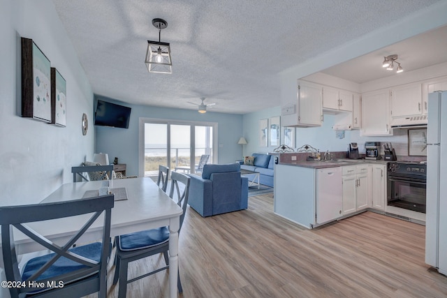 kitchen with white cabinetry, hanging light fixtures, black range, light wood-type flooring, and exhaust hood