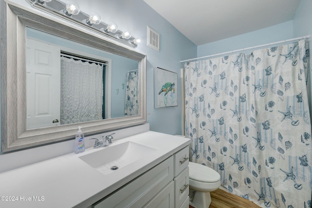 bathroom featuring toilet, vanity, wood-type flooring, and walk in shower