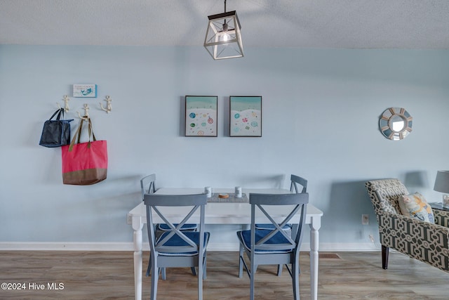 dining room featuring wood-type flooring and a textured ceiling