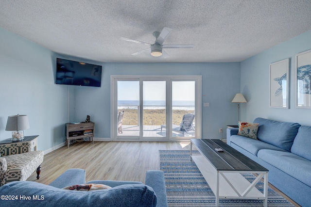 living room featuring light hardwood / wood-style floors, a textured ceiling, and ceiling fan