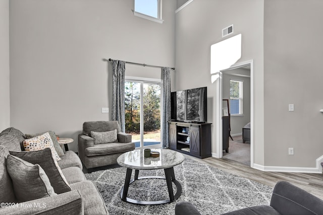 living room with light hardwood / wood-style flooring and a high ceiling