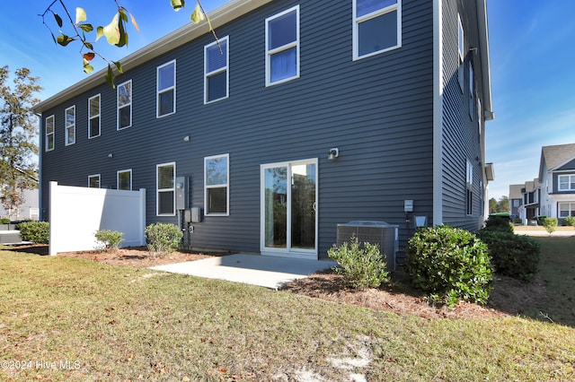 rear view of house with a lawn, cooling unit, and a patio area