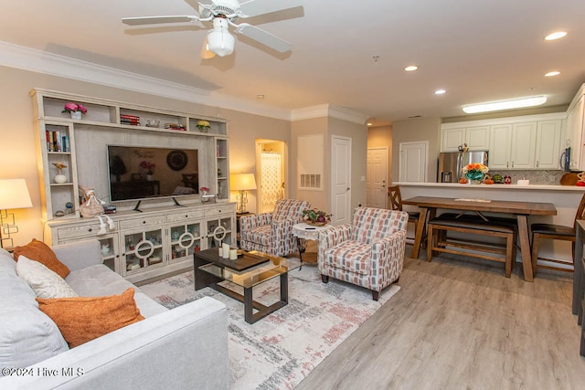 living room featuring ceiling fan, ornamental molding, and light hardwood / wood-style flooring