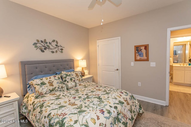 bedroom featuring connected bathroom, sink, hardwood / wood-style floors, and ceiling fan