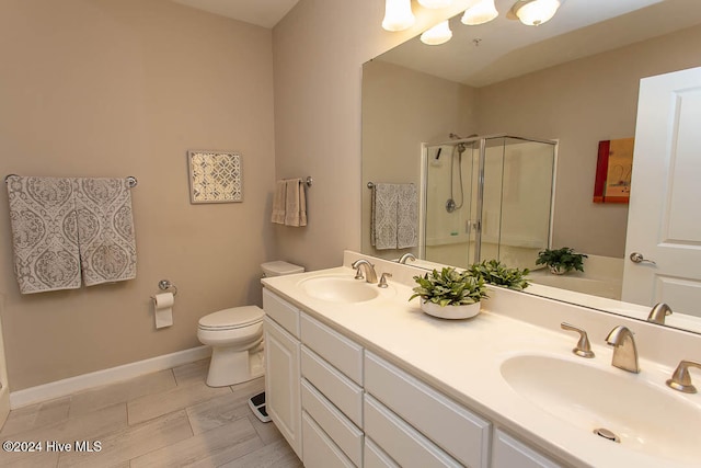 bathroom with a shower with door, vanity, and toilet